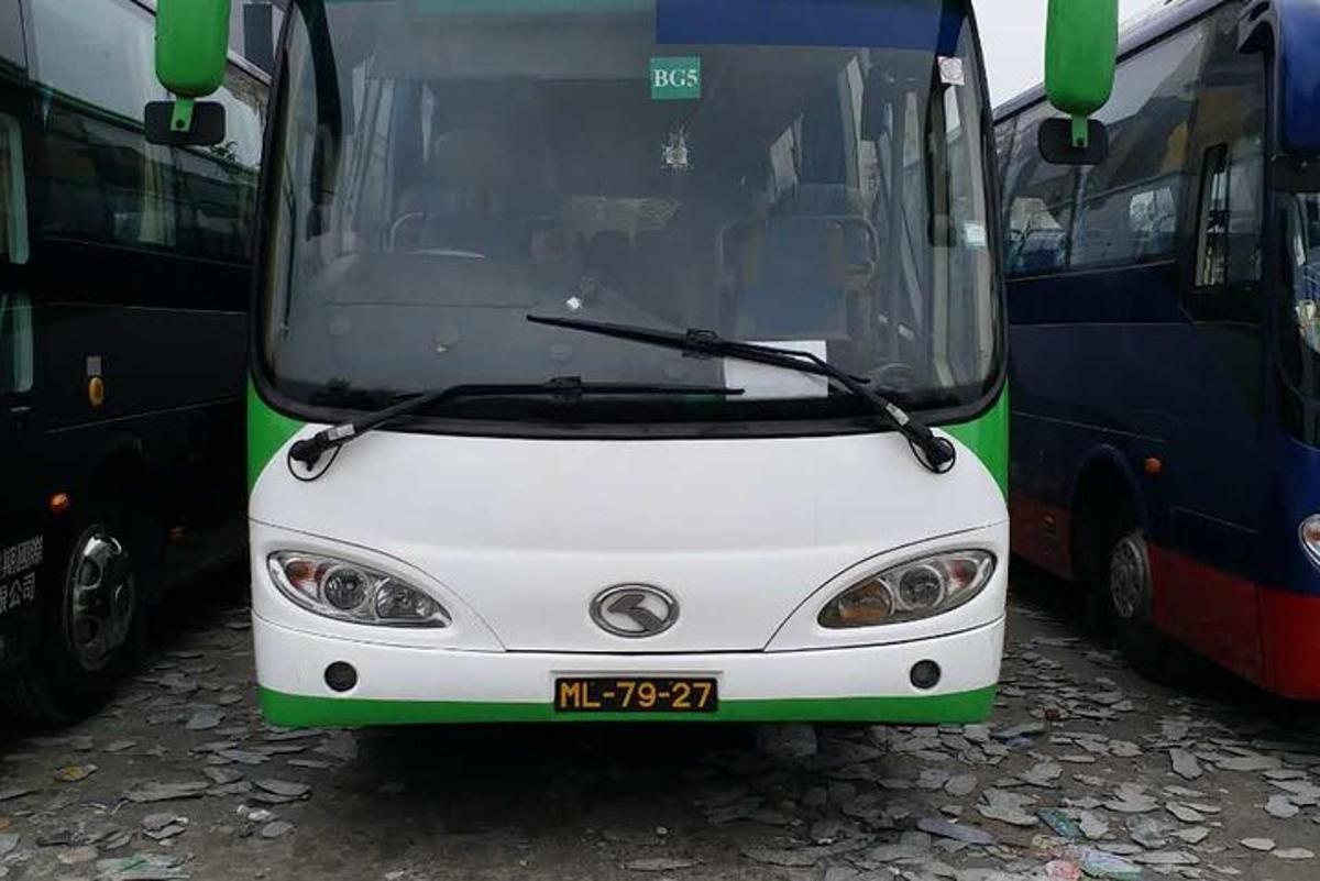 a white and green bus parked next to other buses