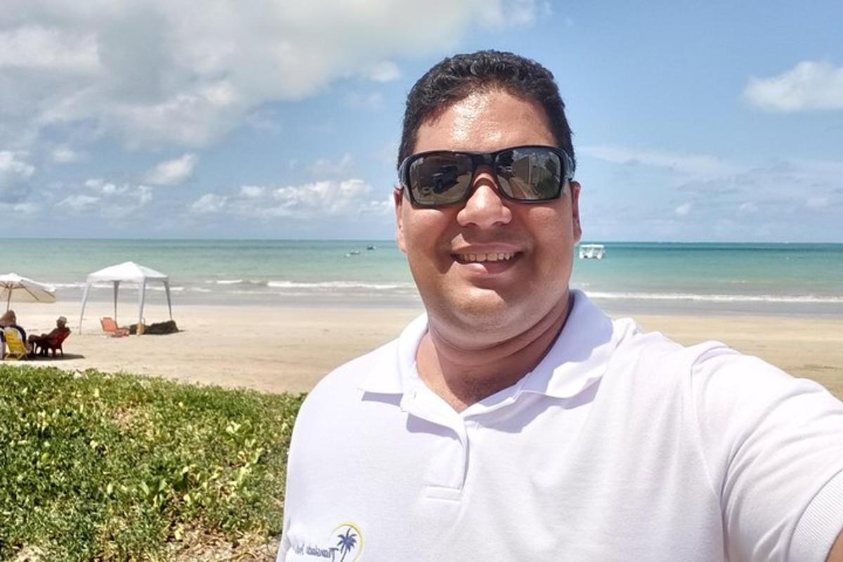 a man wearing sunglasses standing at the beach