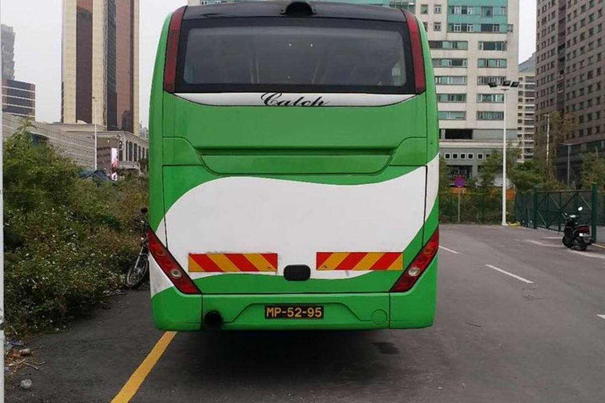 a green and white double decker bus parked in a parking lot