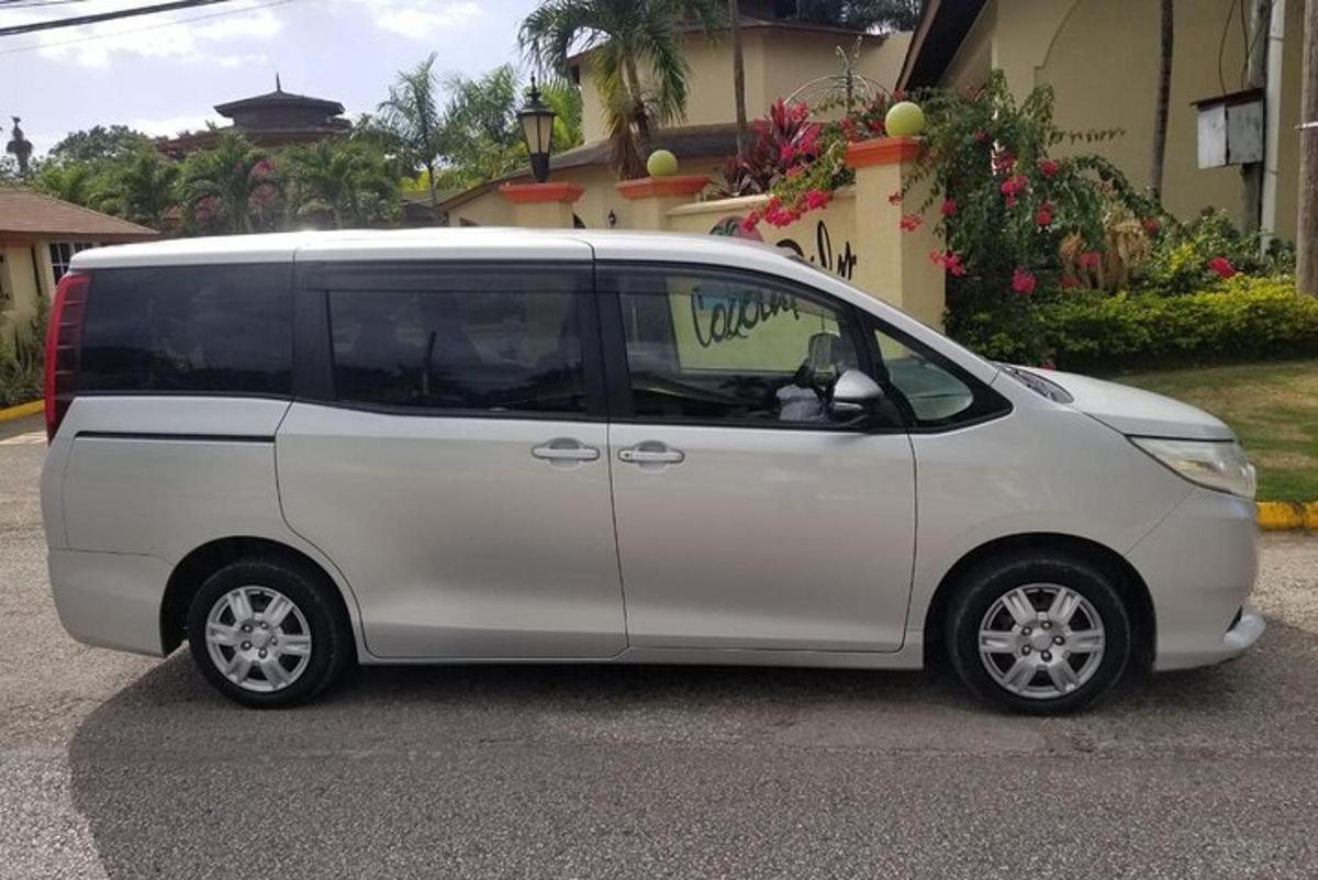 sebuah minivan berwarna putih diletakkan di hadapan sebuah rumah