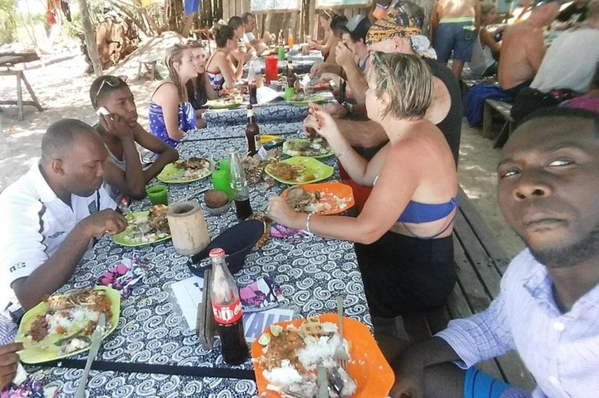 um grupo de pessoas sentadas em mesas compridas comendo comida