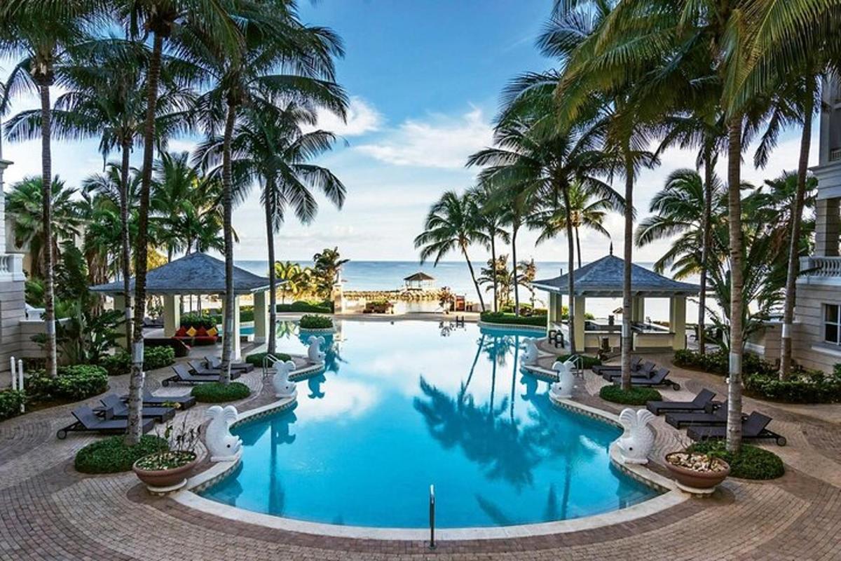 a pool at a resort with palm trees and the ocean