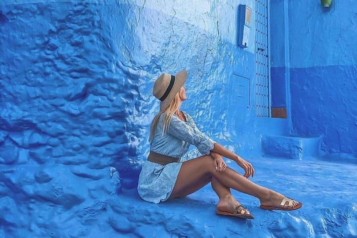 жена у шеширу седи испред мурала