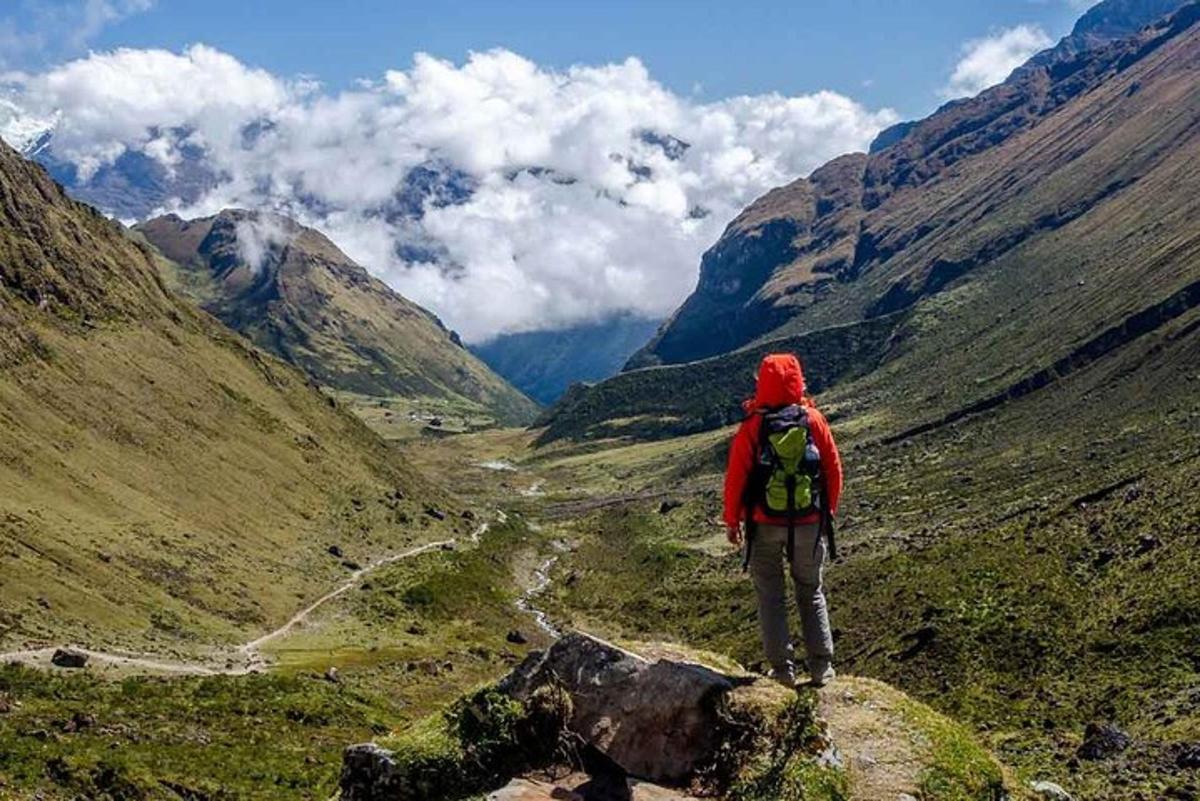 una persona amb una motxilla dempeus al cim d'una muntanya