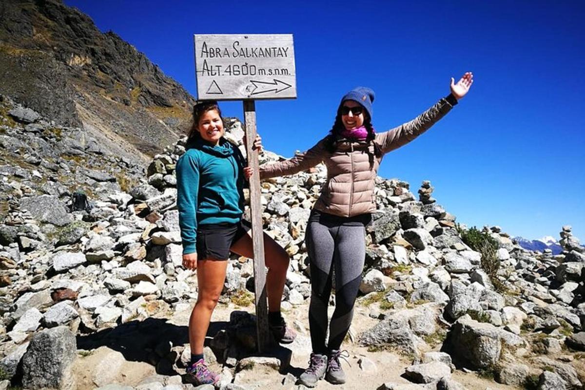 dua wanita berdiri di atas gunung berbatu memegang papan tanda