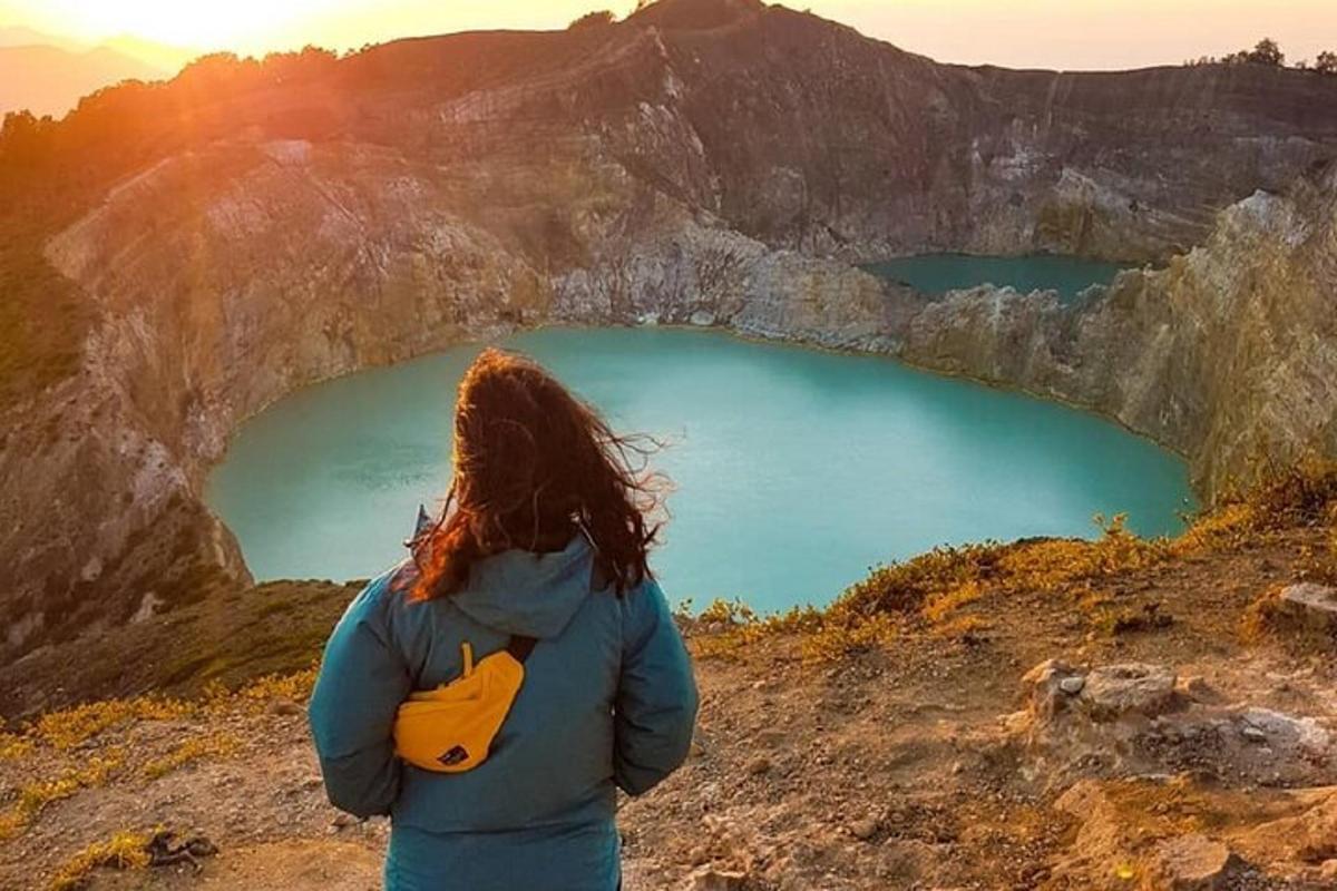 a woman standing on top of a mountain looking at a lake