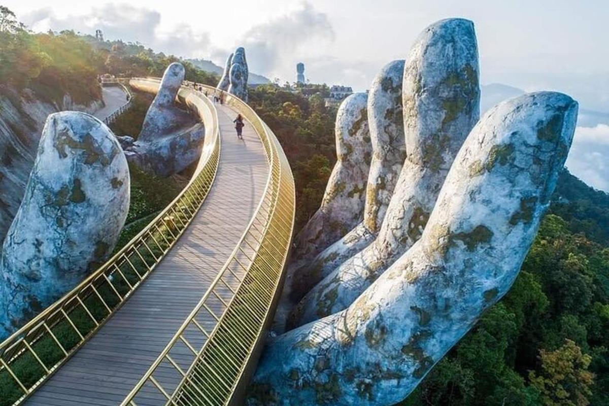 Una vista de un puente colgante con grandes manos de piedra.