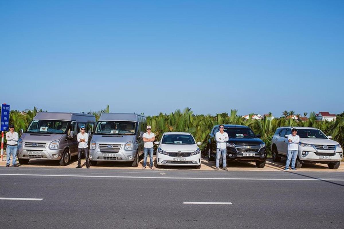grupp inimesi seisab pargitud autode ees