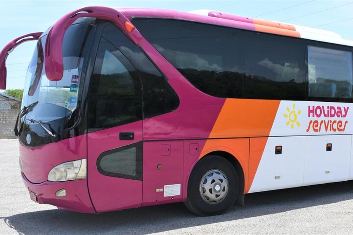 un autobús rosa i taronja aparcat en un aparcament