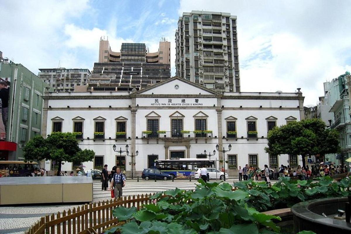 a large white building in a city with tall buildings