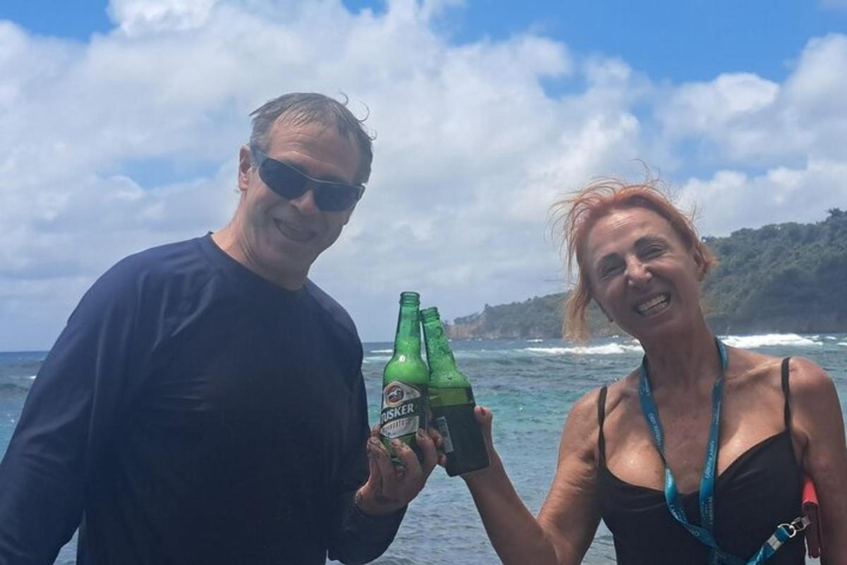 a man and a woman holding beer bottles on the beach
