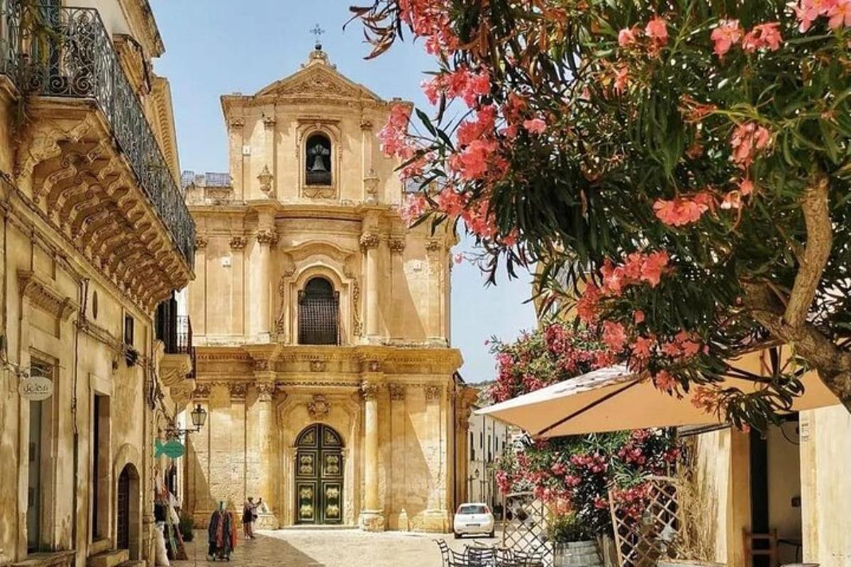 un grande edificio con una torre dell'orologio e fiori rosa