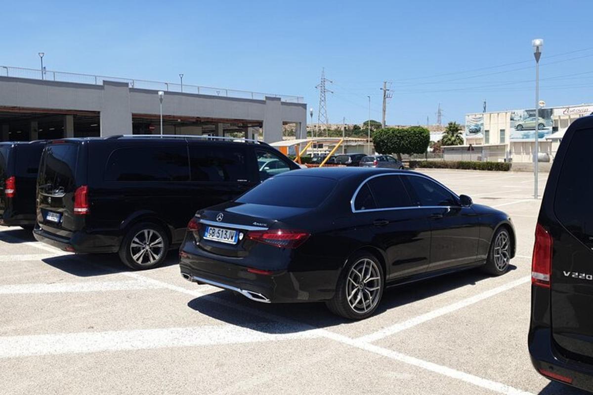 a black car and a black van parked in a parking lot