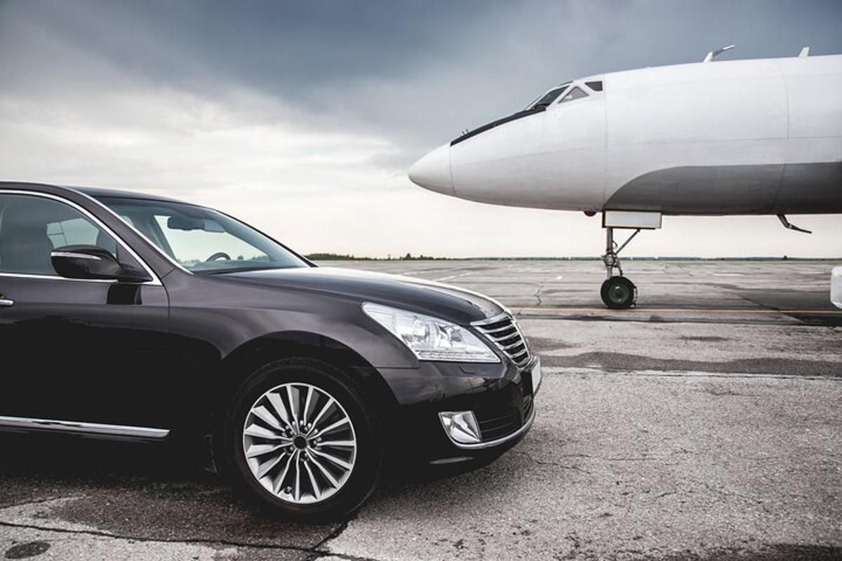 un'auto nera è parcheggiata accanto a un aereo