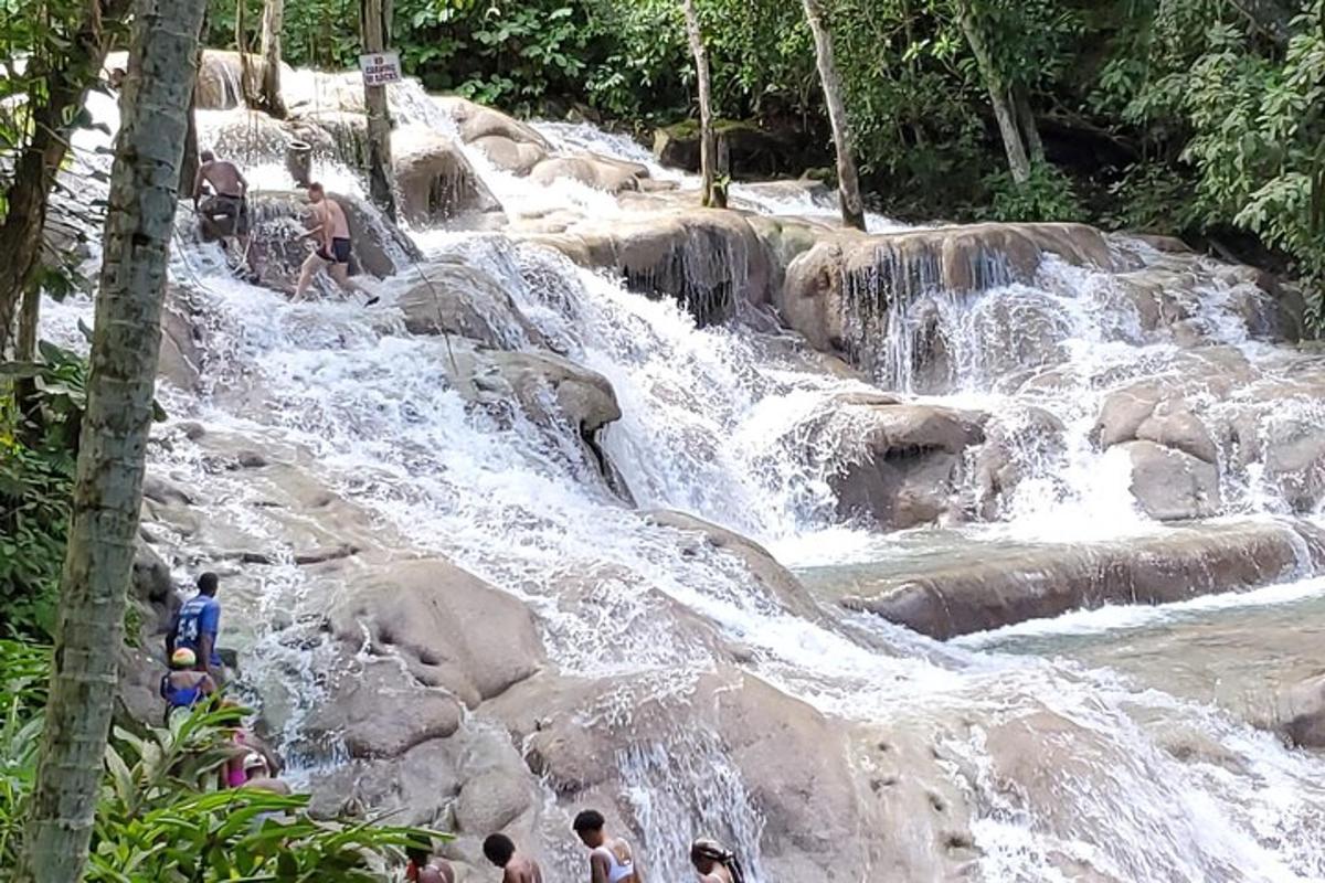 sekelompok orang berdiri di atas batu di air terjun