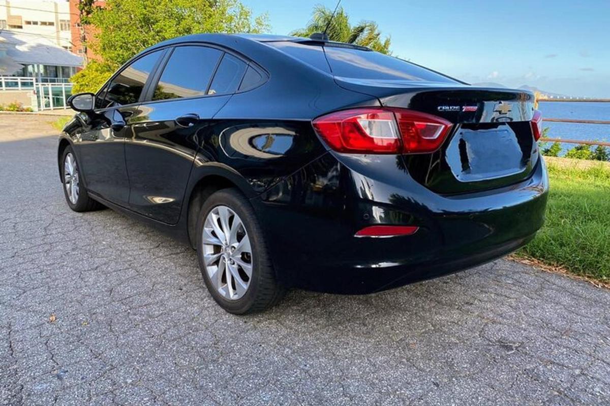 a black car parked on a road near the water