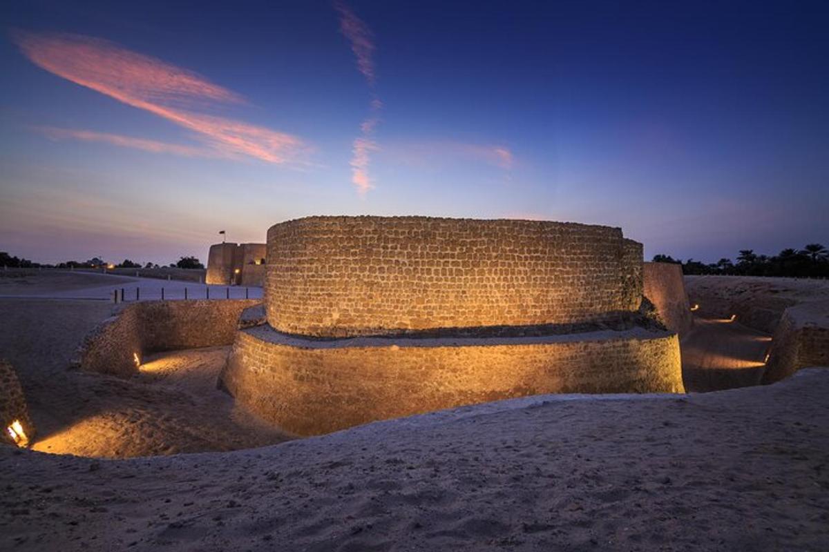 a stone bench sitting in the sand at sunset