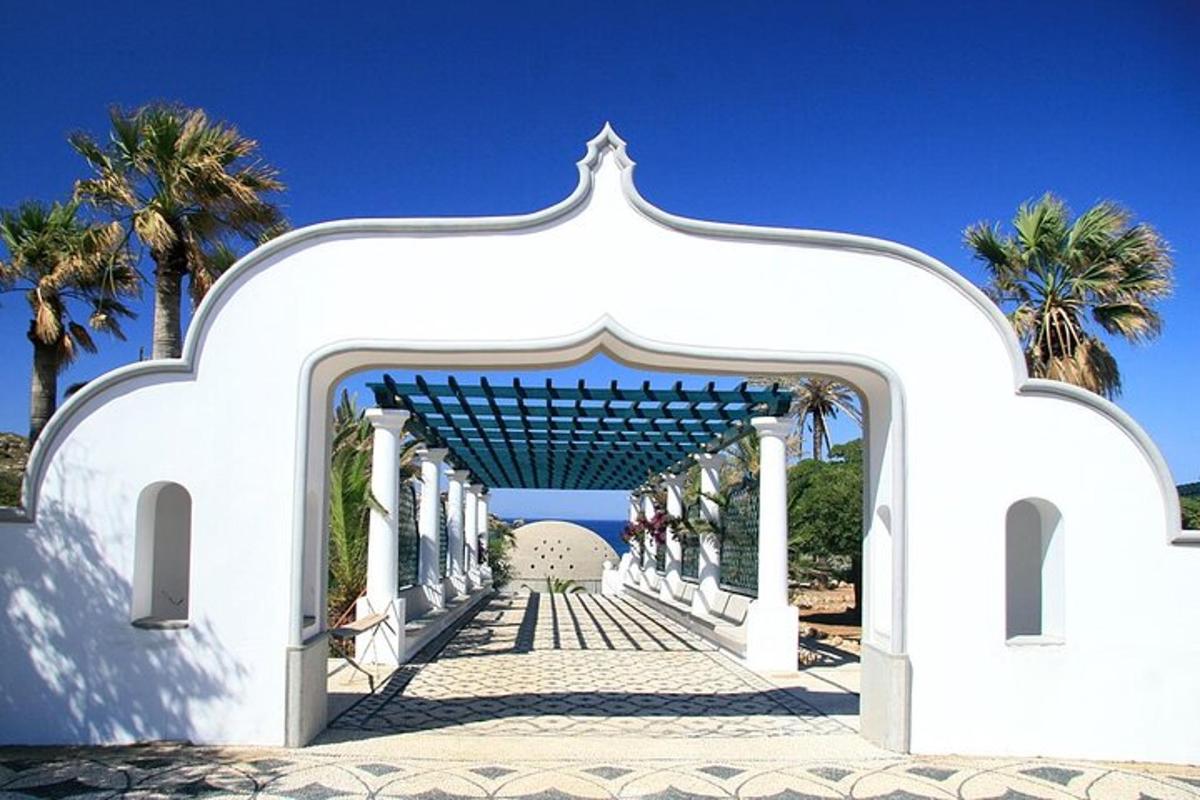 Un arco blanco con palmeras al fondo.