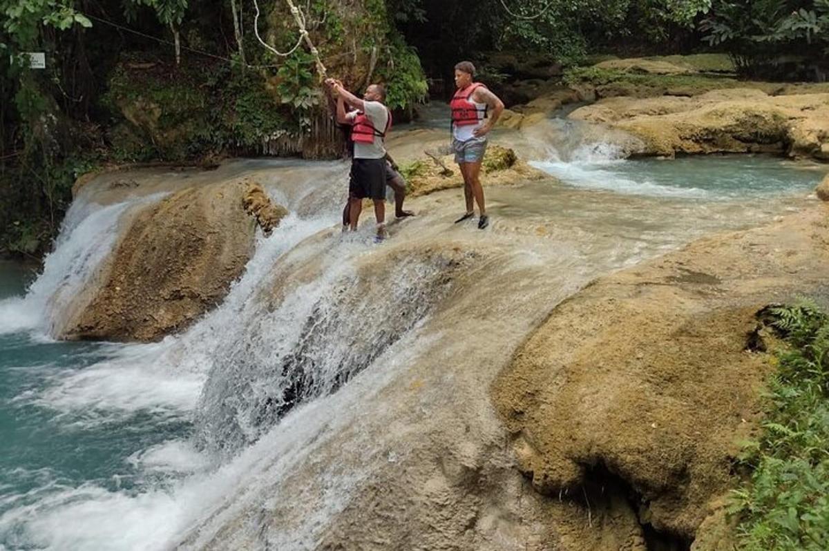 dua pria berdiri di atas batu dekat air terjun