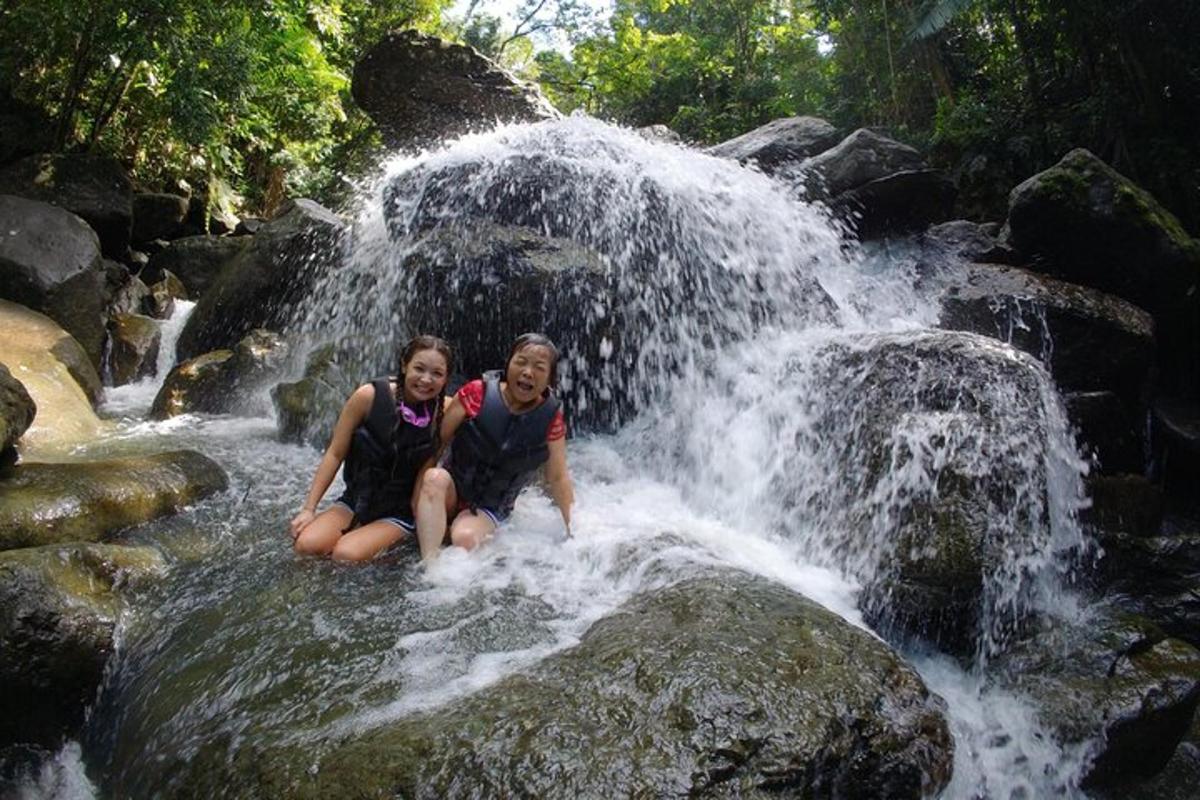 two women sitting on rocks in a waterfall