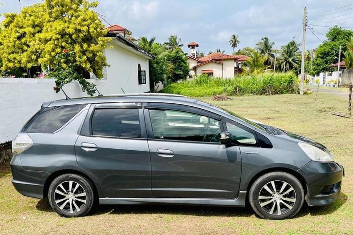 a gray car parked in a field next to a house