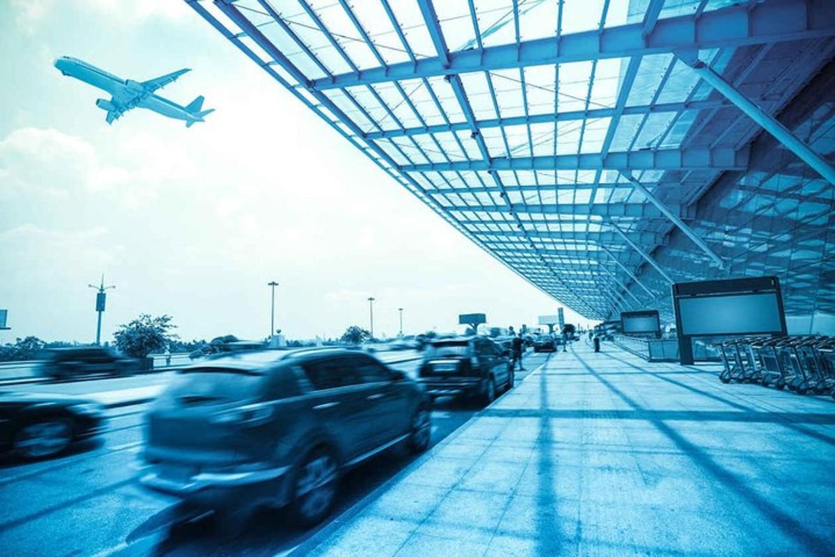 an airplane is flying over cars parked at an airport