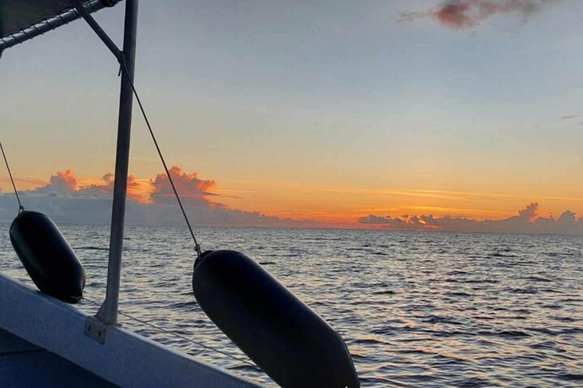 a boat in the ocean with a sunset in the background