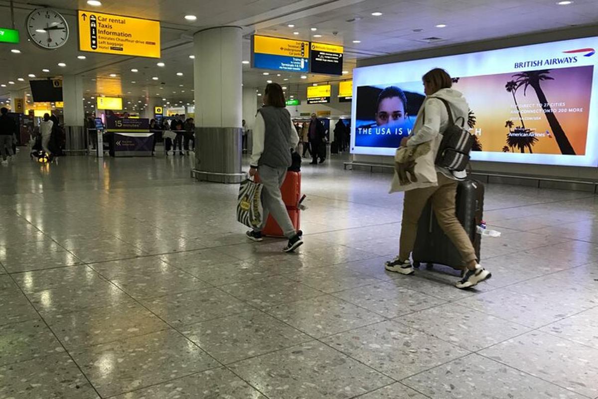 Három ember sétál át a repülőtéren a csomagjaikkal