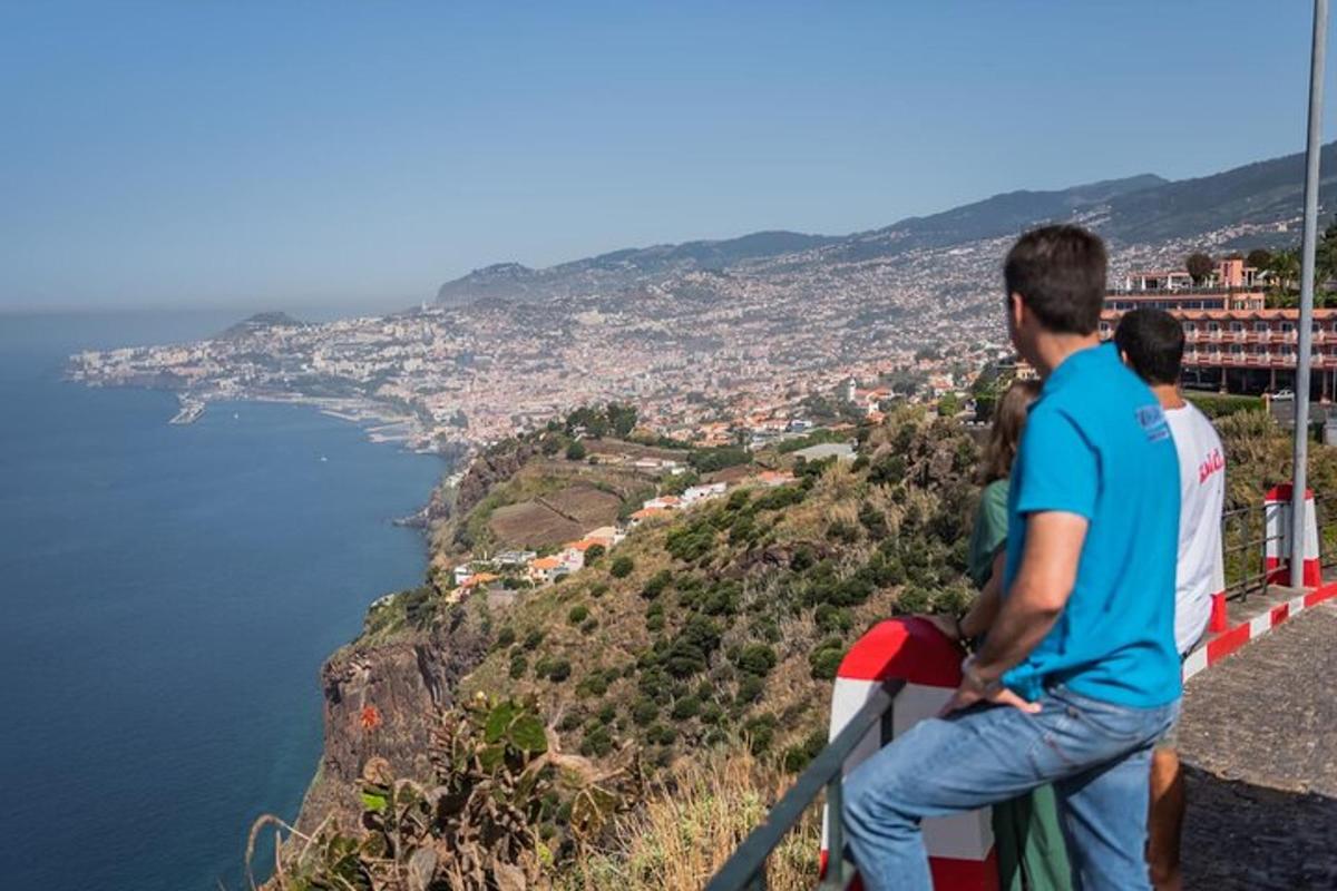 un gruppo di persone sedute sul bordo di una scogliera che domina una città