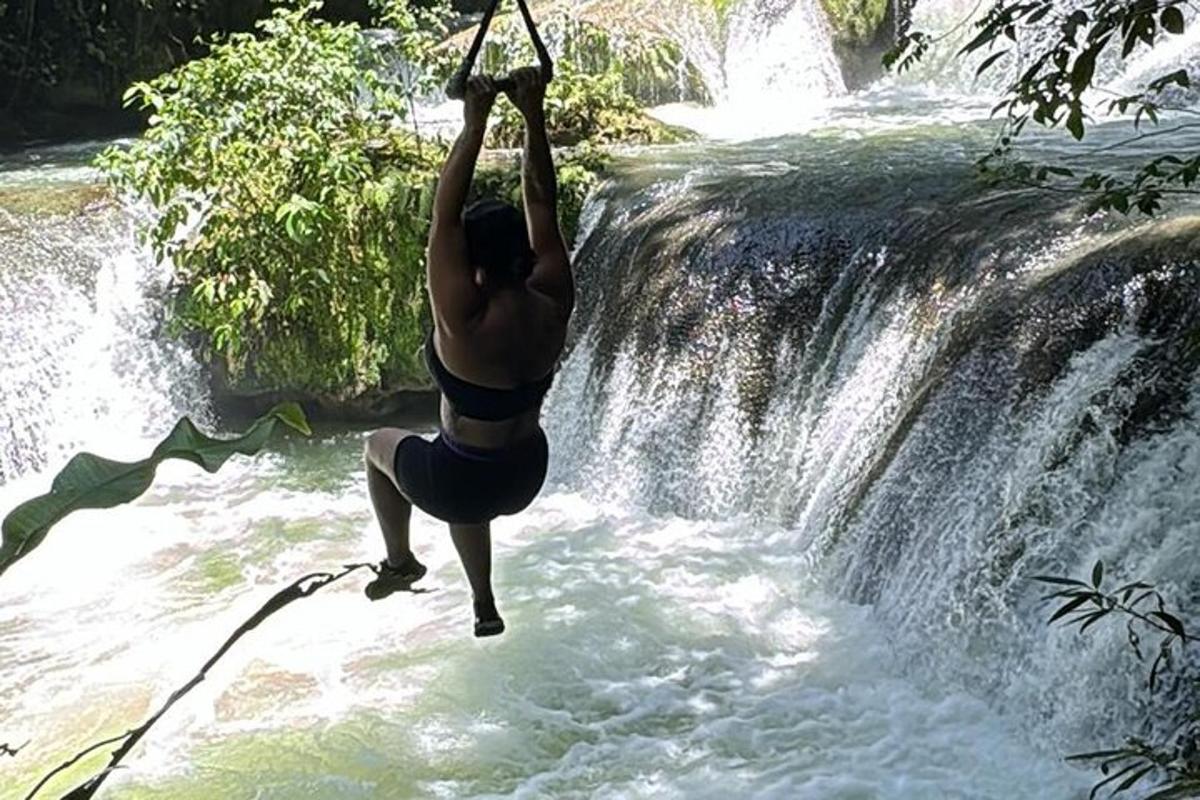 uma pessoa pendurada em uma corda sobre uma cachoeira