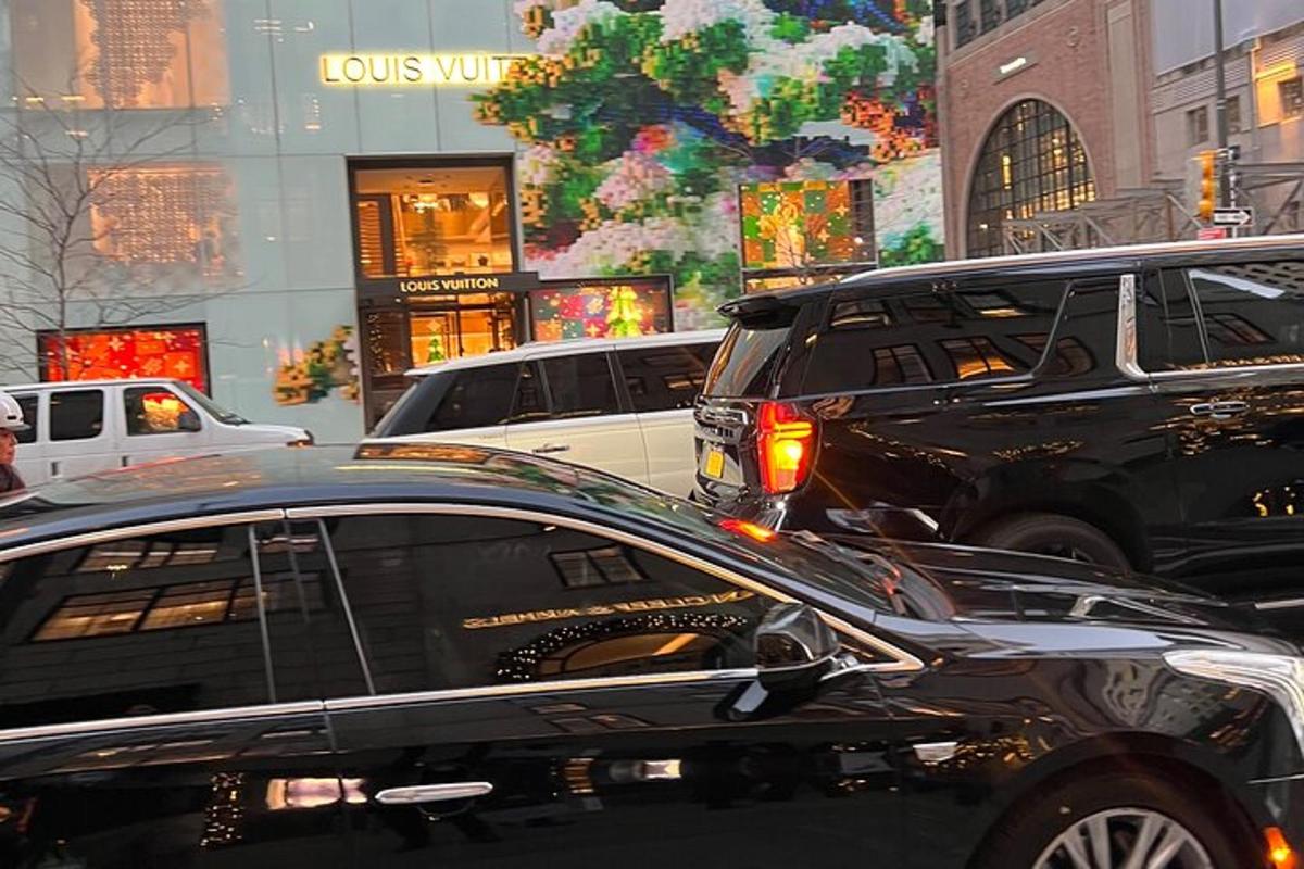 a black car driving down a busy city street