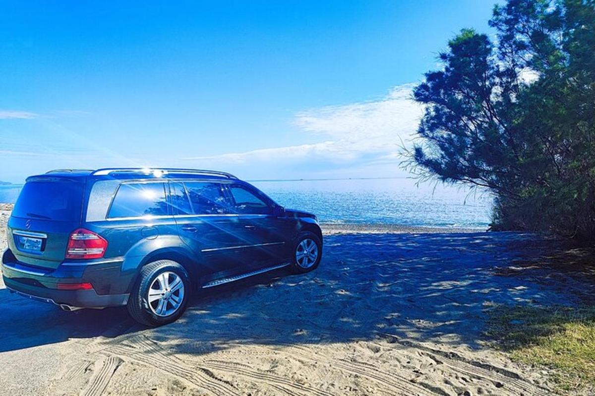 a blue suv parked on the sand near the ocean