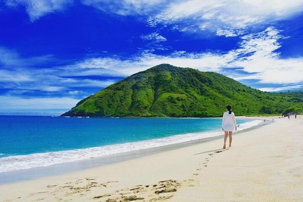 a woman standing on a beach with a mountain in the background