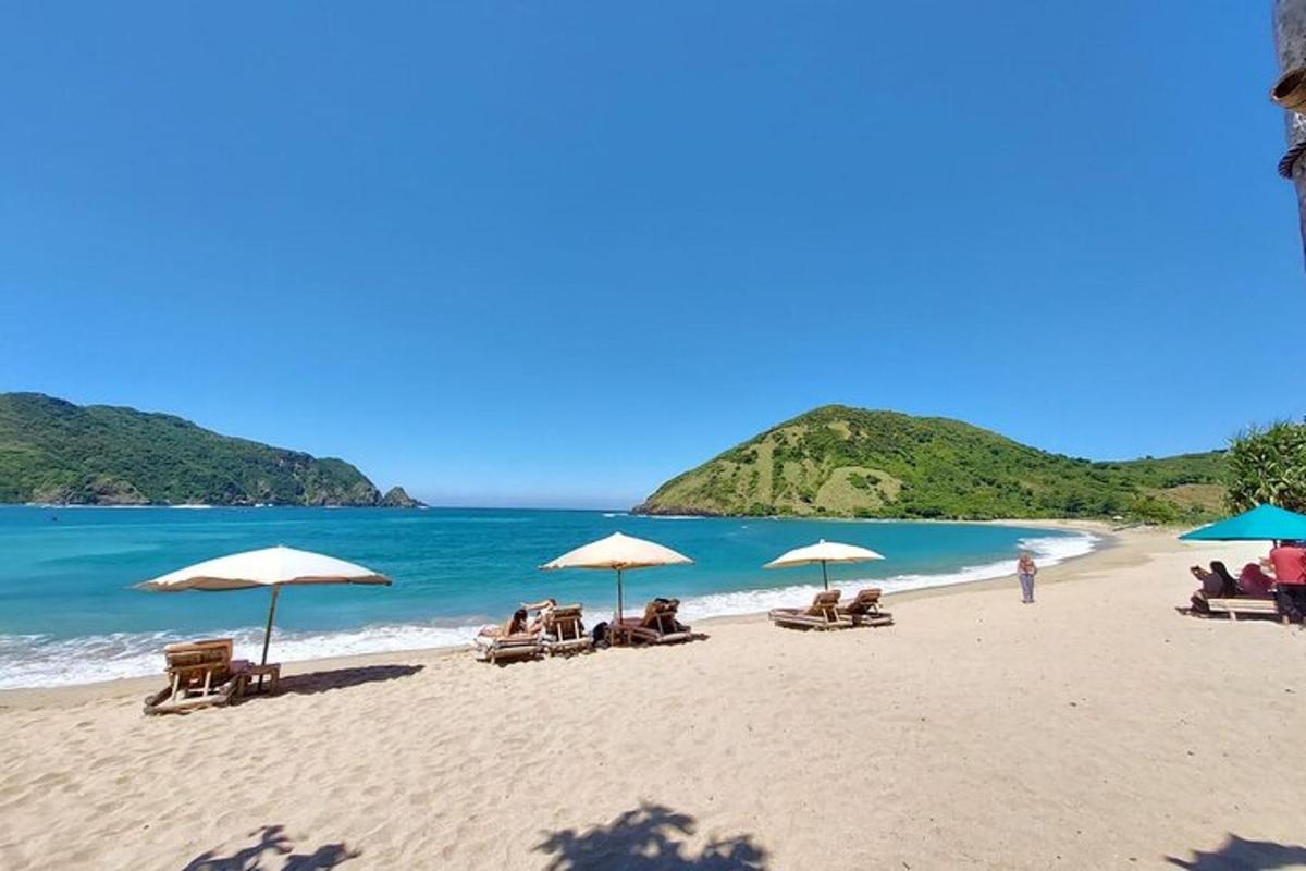 一群人坐在沙滩上，撑着遮阳伞