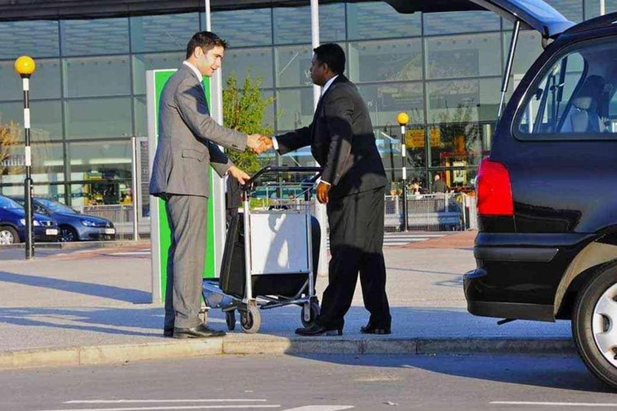zwei Männer schütteln sich vor einem Auto die Hände