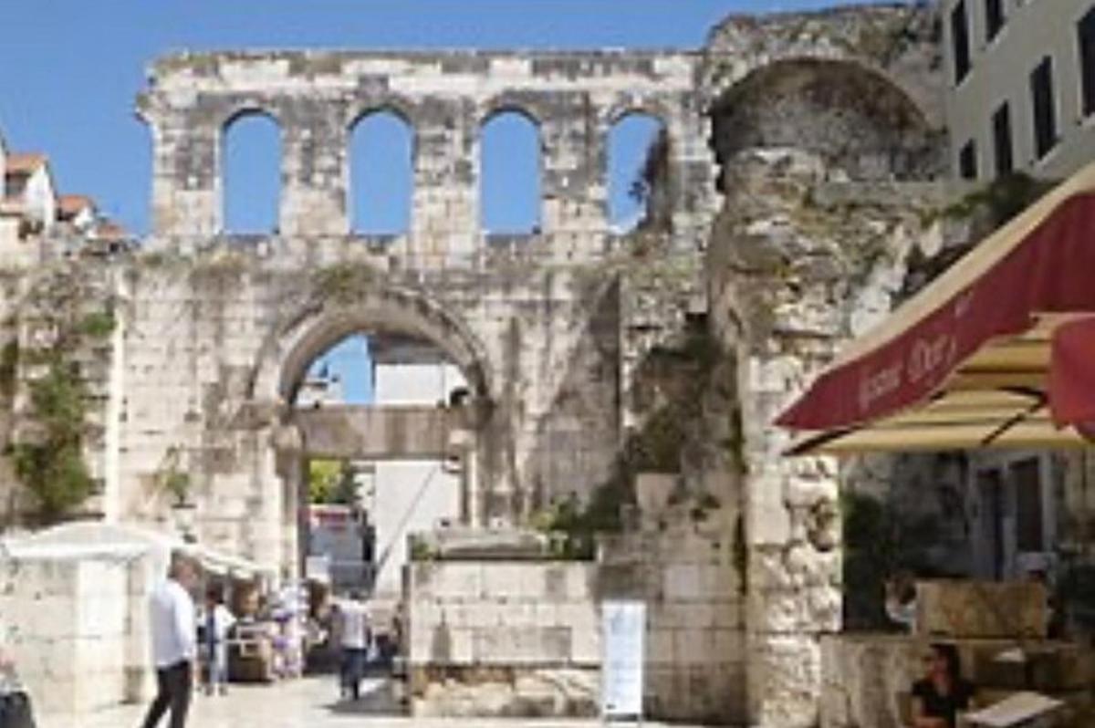 un vecchio arco di pietra con persone che camminano in una strada