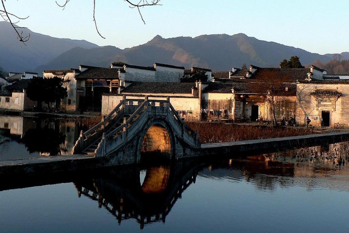 a bridge over a body of water with buildings and mountains