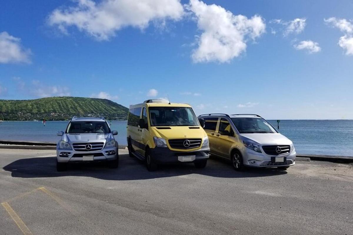 tři auta zaparkovaná na parkovišti u oceánu
