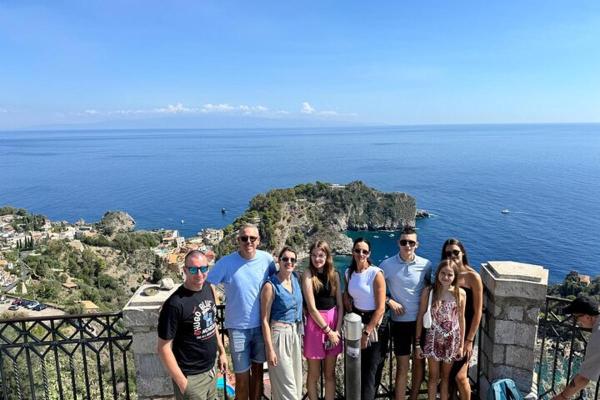 a group of people posing for a picture on a ledge overlooking the ocean