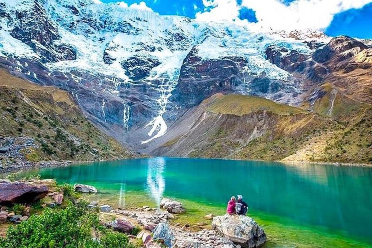 dua orang berdiri di atas batu berhampiran tasik gunung
