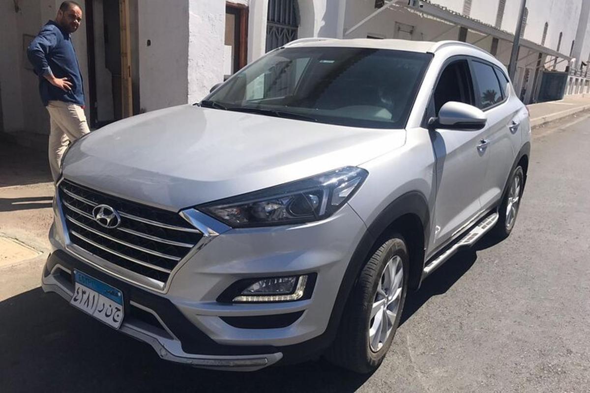 Un hombre está parado junto a un coche blanco.