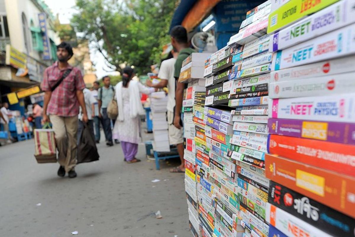 a group of people walking down a street next to a stack of books