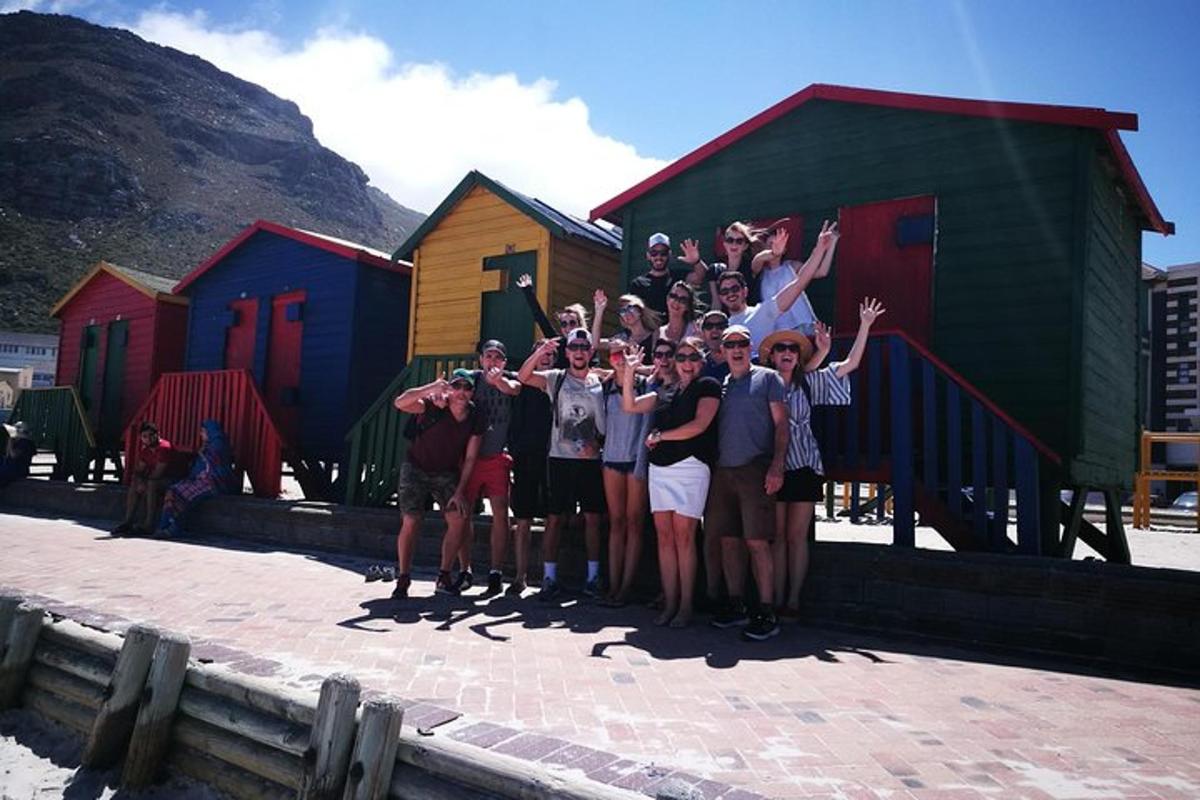 un gruppo di persone in piedi davanti a colorate cabine sulla spiaggia