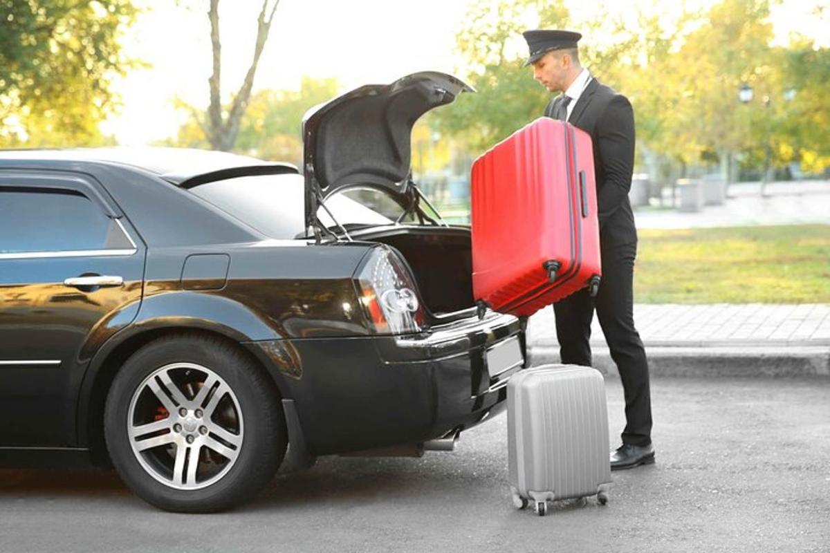 một người đàn ông đứng cạnh một chiếc xe với một chiếc vali