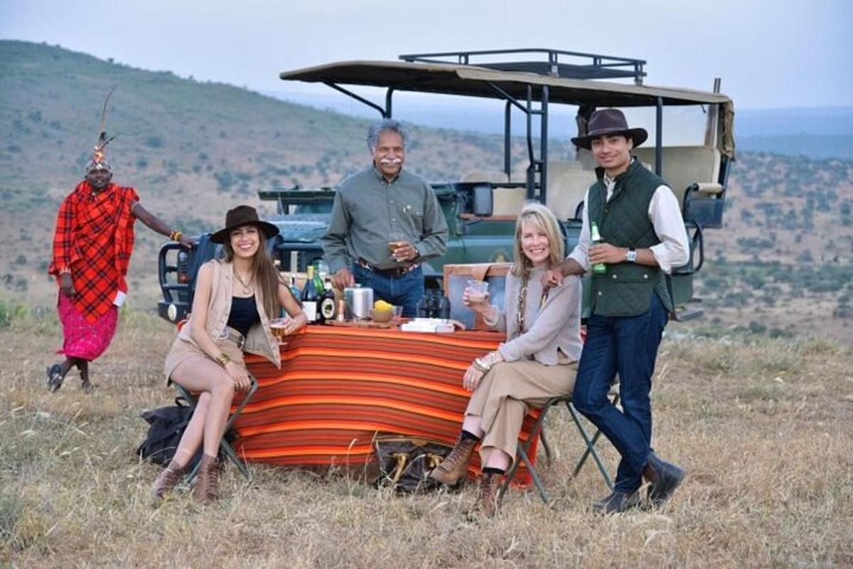 een groep mensen die rond een tafel in een veld zitten
