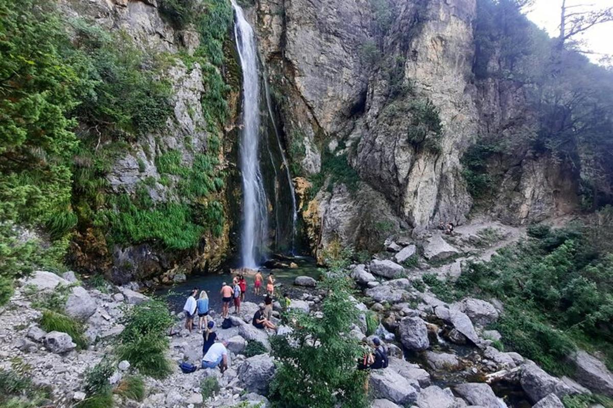 um grupo de pessoas em pé em frente a uma cachoeira