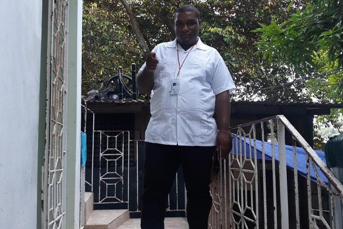 um homem de camisa branca parado ao lado de um portão