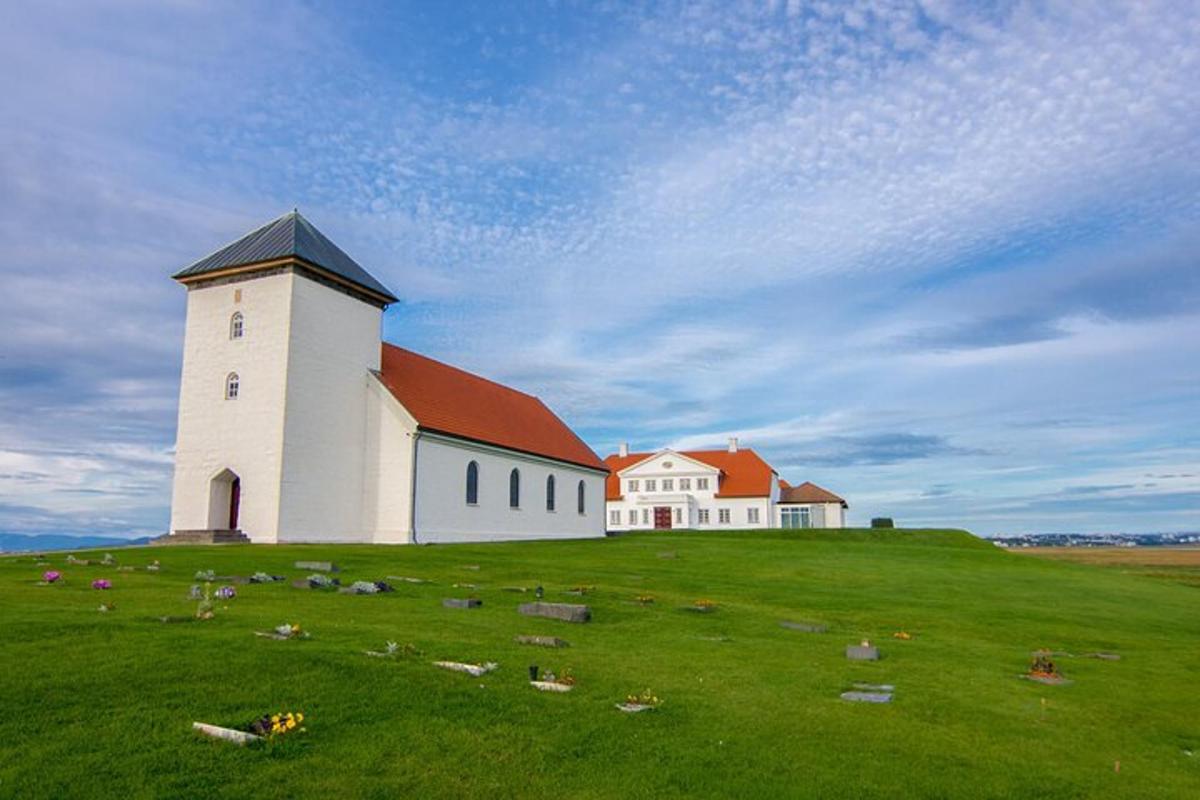velká bílá budova na travnatém kopci s kostelem