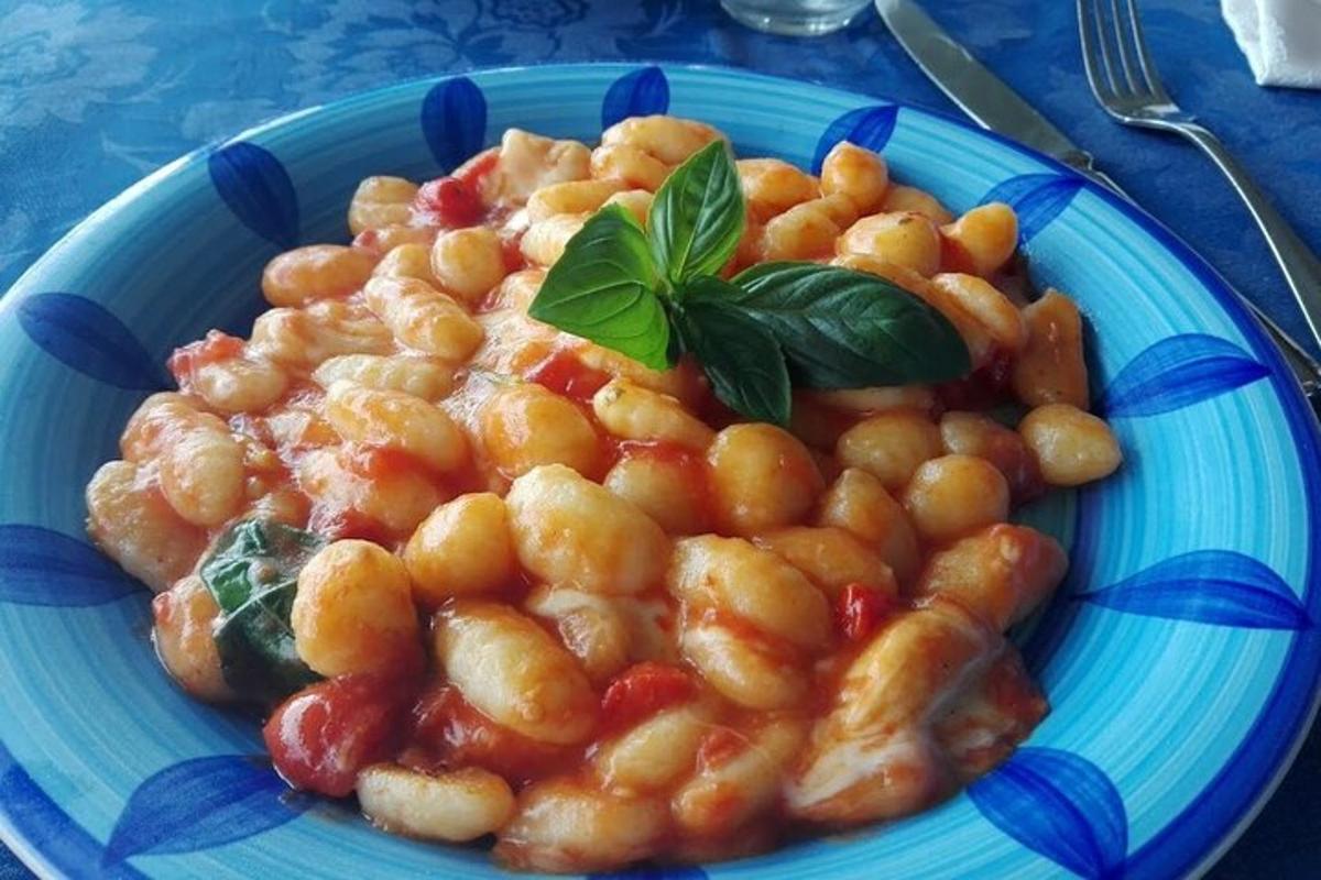 un piatto blu di cibo con fagioli e una foglia verde sopra