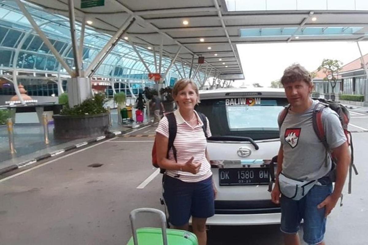 seorang lelaki dan seorang wanita berdiri di hadapan sebuah kereta